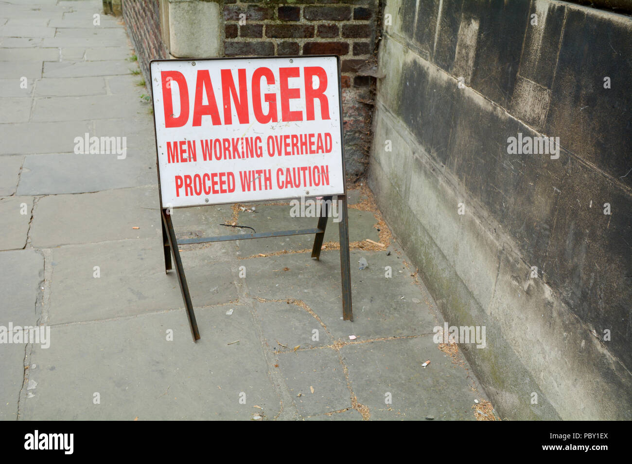Pericolo - gli uomini al lavoro in alto - Procedere con cautela sul lato marciapiede Foto Stock