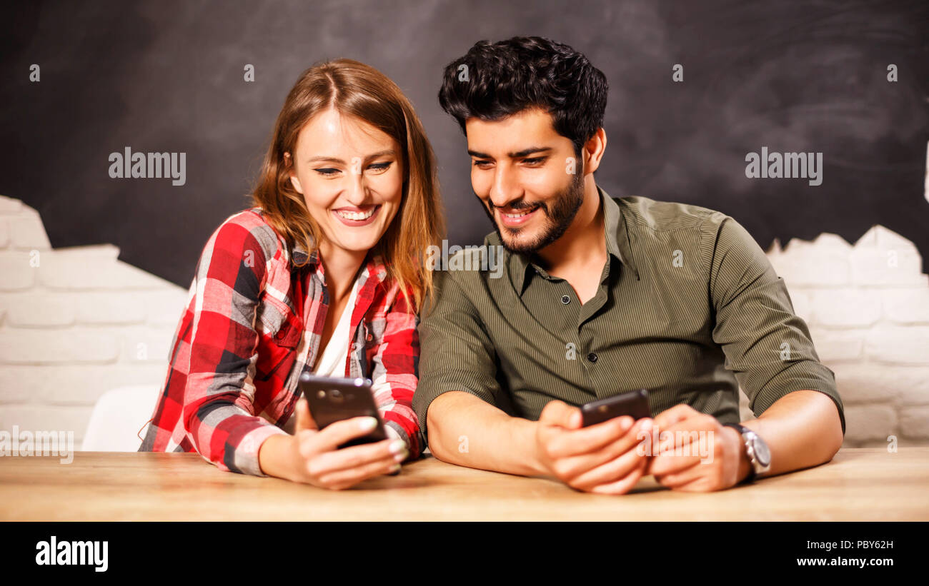 Felice giovane coppia adorabile seduto e guardando diverse foto in lo smartphone alla luce office Foto Stock