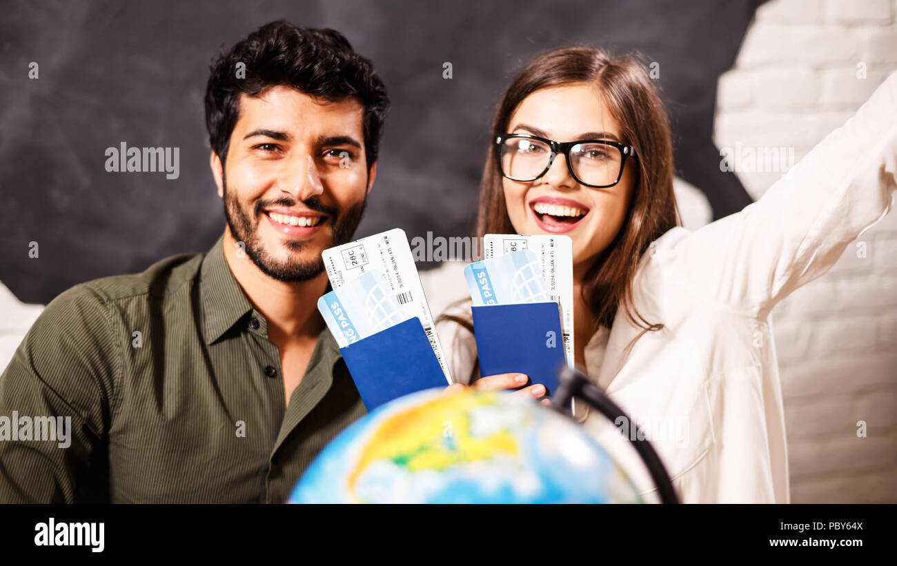 Coppia giovane sorridente con la mappa del globo e passaporti, essi la scelta di posto per i viaggi Foto Stock