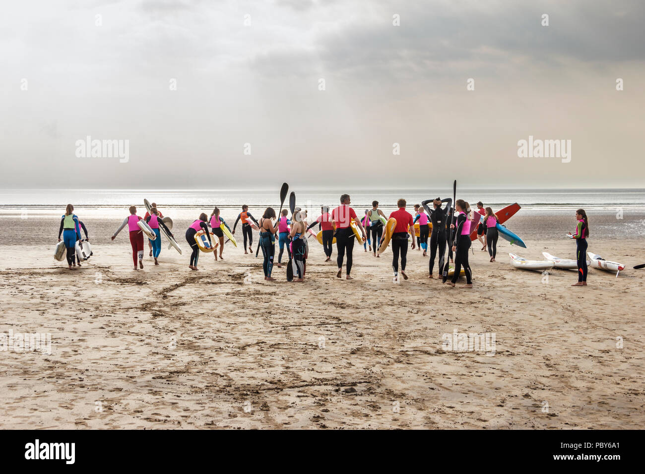 Un grande gruppo di surfers, surf sciatori e kayakers incontro sulla spiaggia di Condino, Devon, Regno Unito Foto Stock