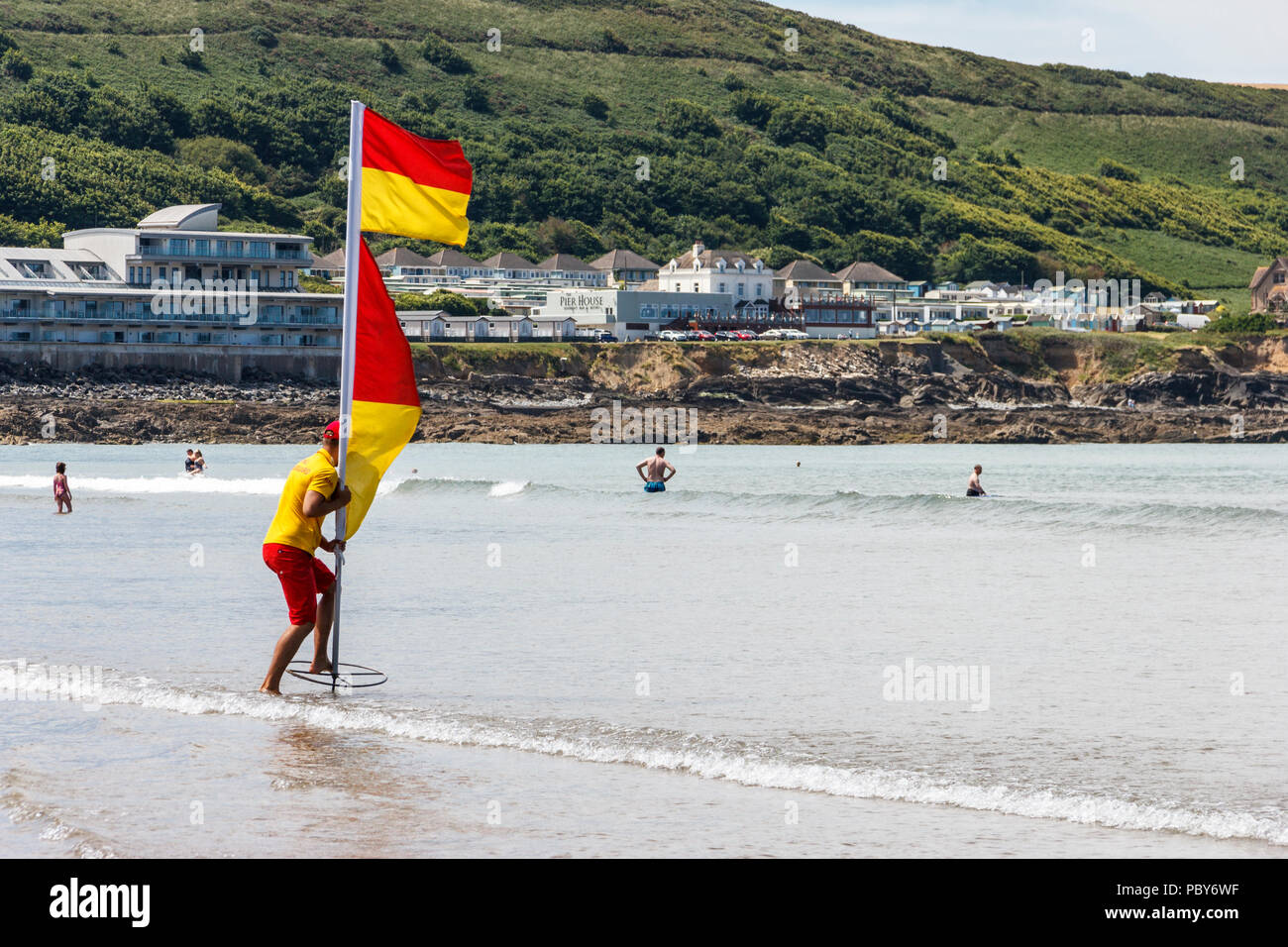Bagnino RNLI mettendo un marcatore flag nella spiaggia di Condino, Devon, Regno Unito Foto Stock