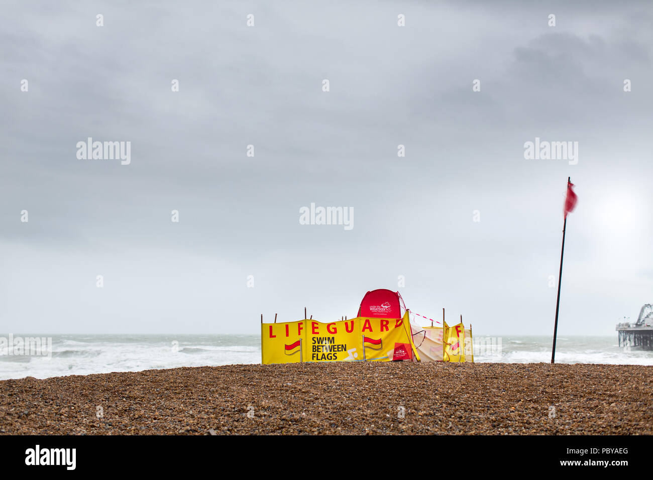 Vista di un bagnino base sulla Spiaggia di Brighton. La bandiera rossa è volare e avviso di persone a nuotare tra le bandiere ma è troppo ruvida per nuotare nel mare. Foto Stock