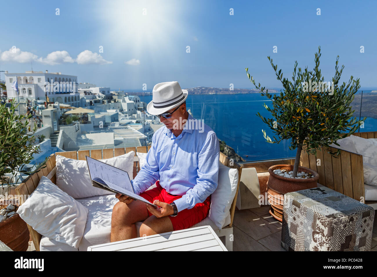 Uomo in un ristorante in riva al mare a guardare il menu e fa un ordine alimentare Foto Stock