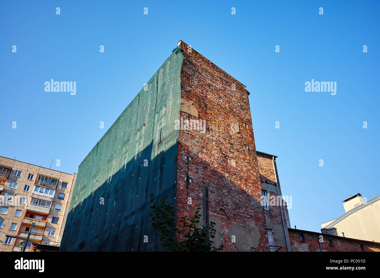 Vecchio edificio coperto con verde rete di sicurezza prima di demolizione. Foto Stock
