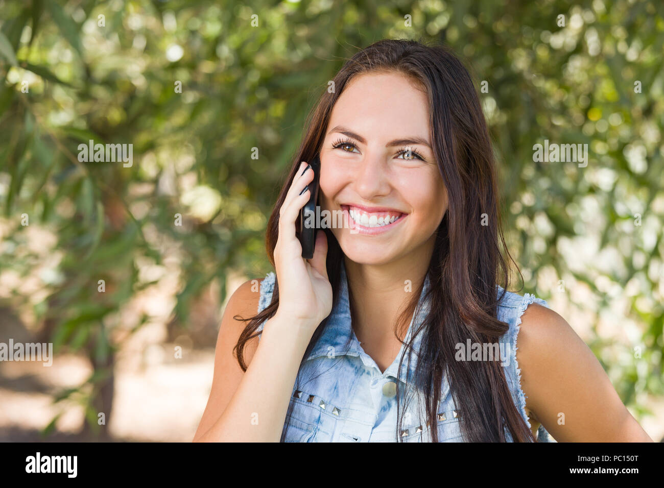 Attraente felice razza mista giovani femmine parlando al cellulare al di fuori. Foto Stock