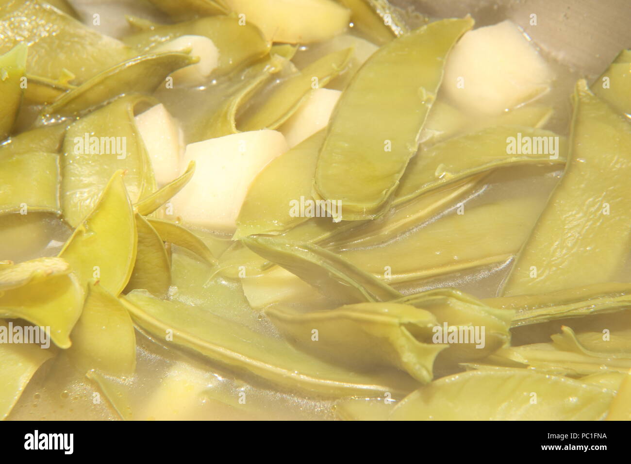 Baccelli di piselli e patate essendo realizzati in zuppa Foto Stock