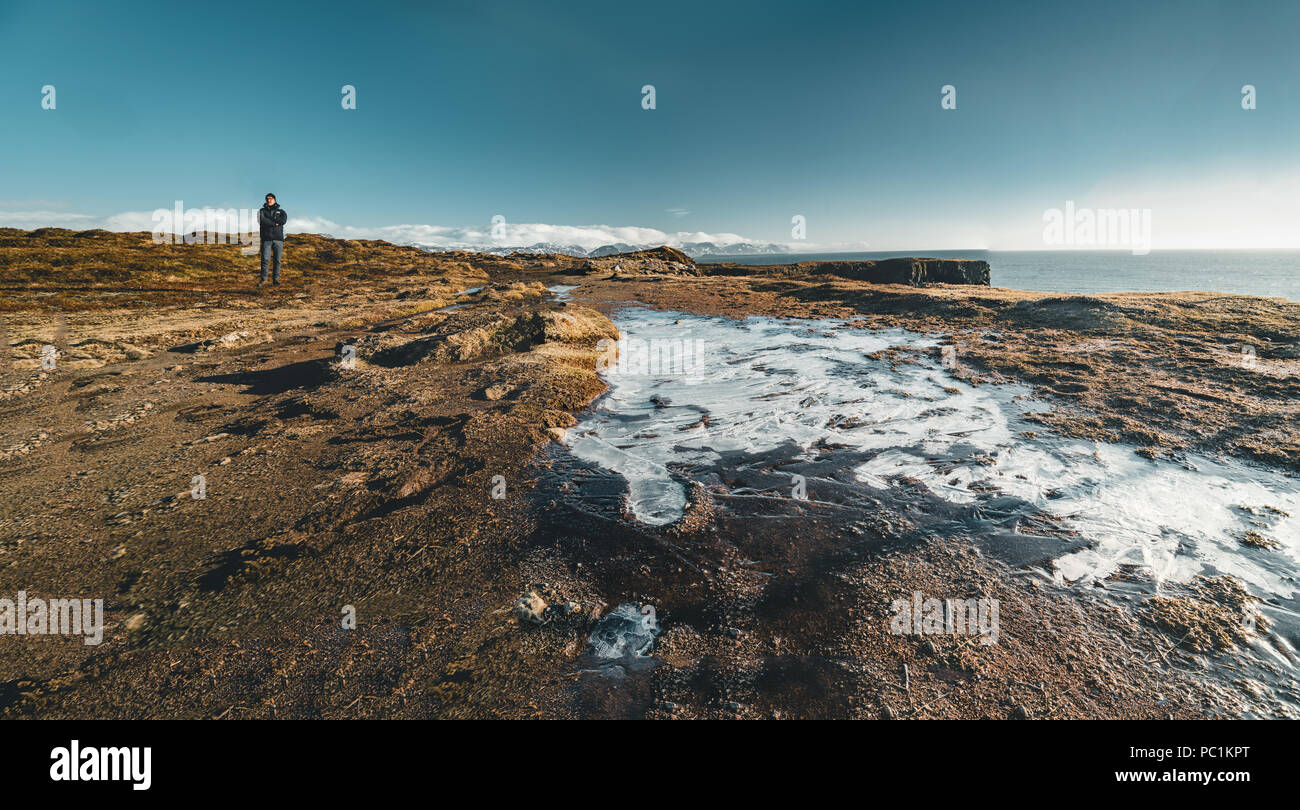 Arnarstapi , Islanda - Maggio 2018: giovane maschio permanente turistico nei pressi di un piccolo ghiacciaio in una bella giornata con il bue sky. Foto Stock