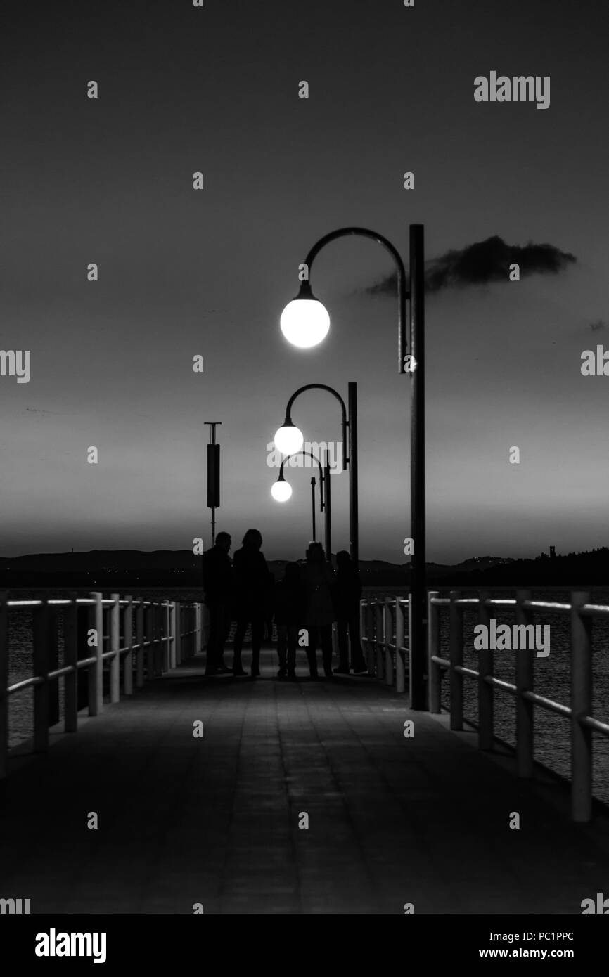 Alcune persone su un molo presso il lago Trasimeno (Umbria, Italia) al tramonto Foto Stock