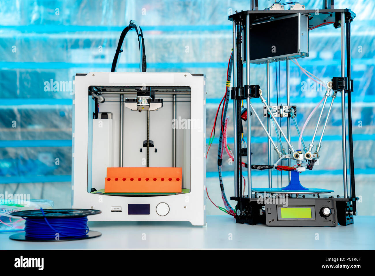 ABS e PLA filament accanto alla stampante 3D. Bobine di plastica Foto Stock