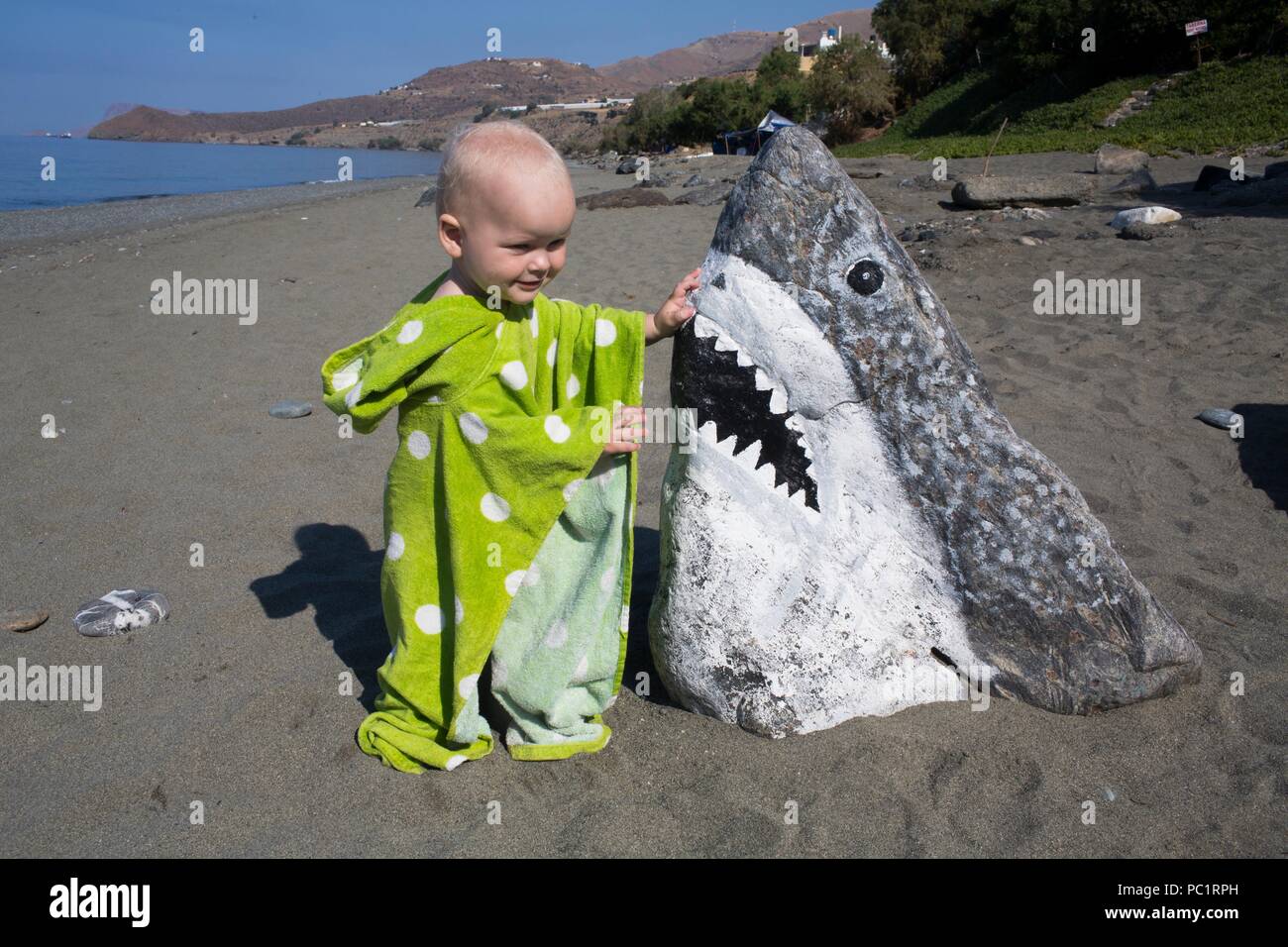 Ragazzo giocando con la shark (dipinta su una roccia) Foto Stock