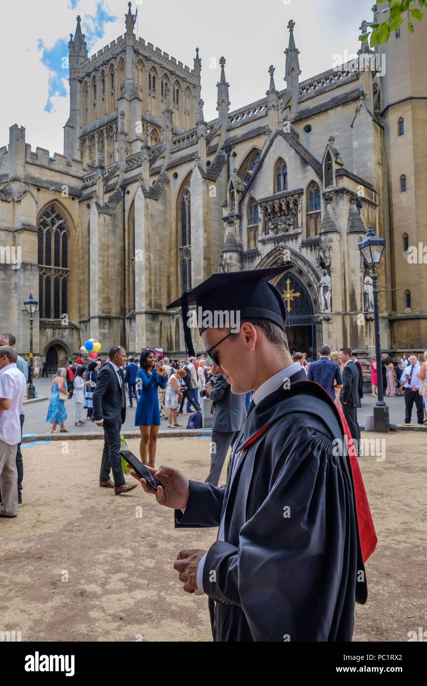 Studente dopo la laurea controllando il suo telefono cellulare?telefono cellulare dopo la cerimonia di laurea in Bristol< WEST of England Regno Unito. Foto Stock
