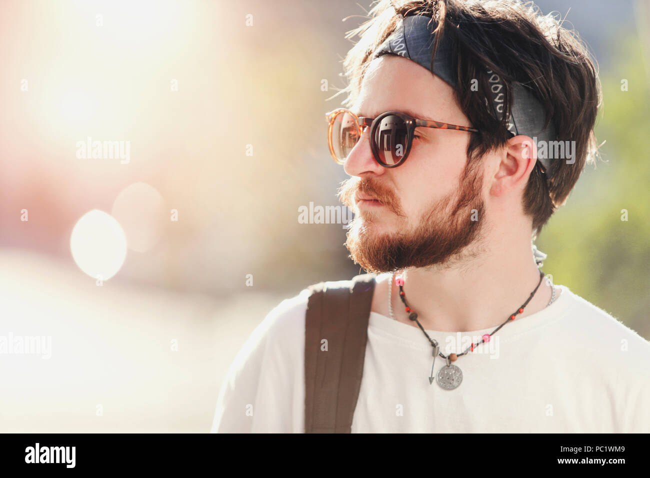 Bello barbuto hipster boy in occhiali da sole passeggiate al tramonto sulla  strada Foto stock - Alamy