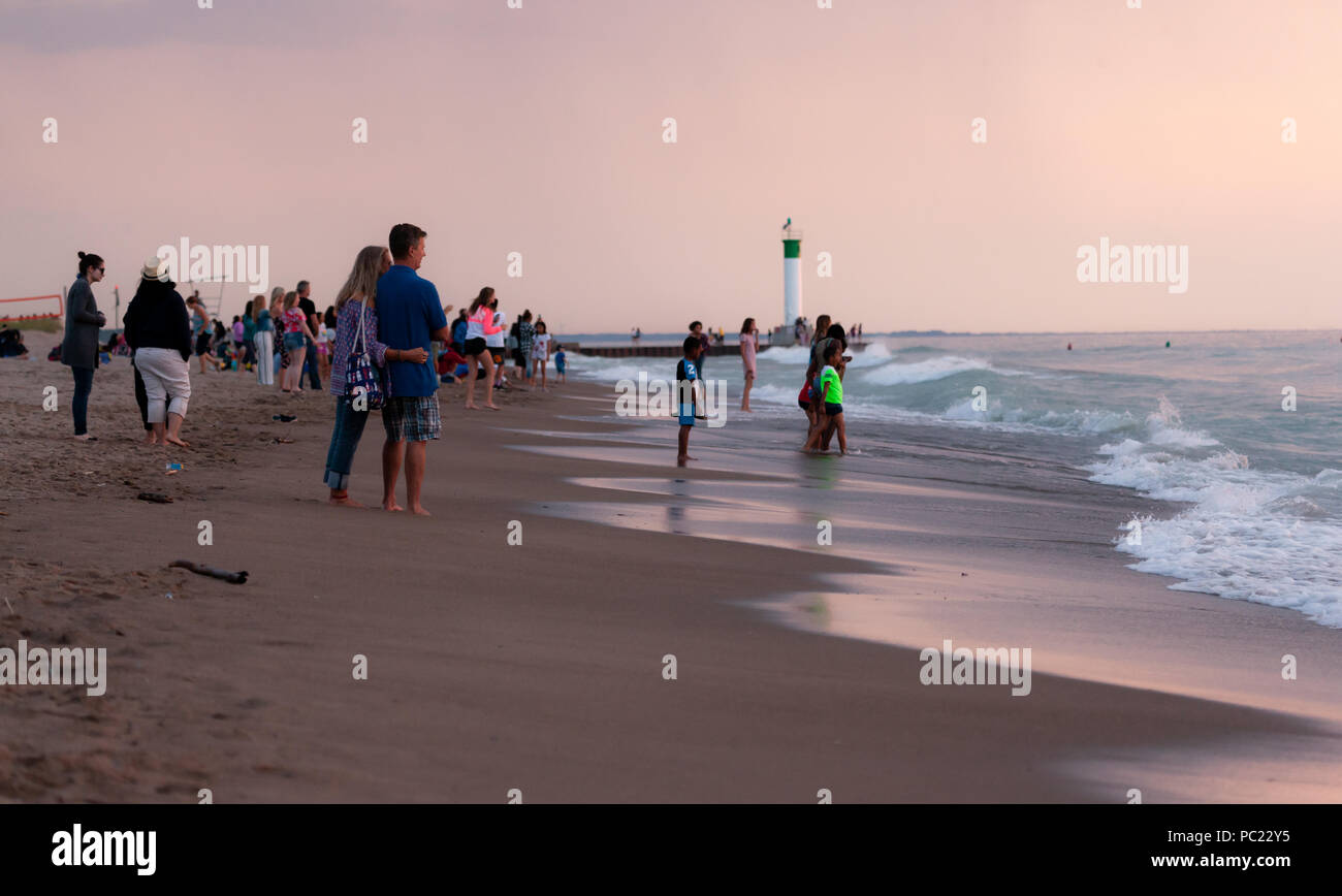 La visione di un tramonto mozzafiato iniziano a slittare sotto la horizion mentre le persone si radunano sulla spiaggia di Grand Bend. Foto Stock