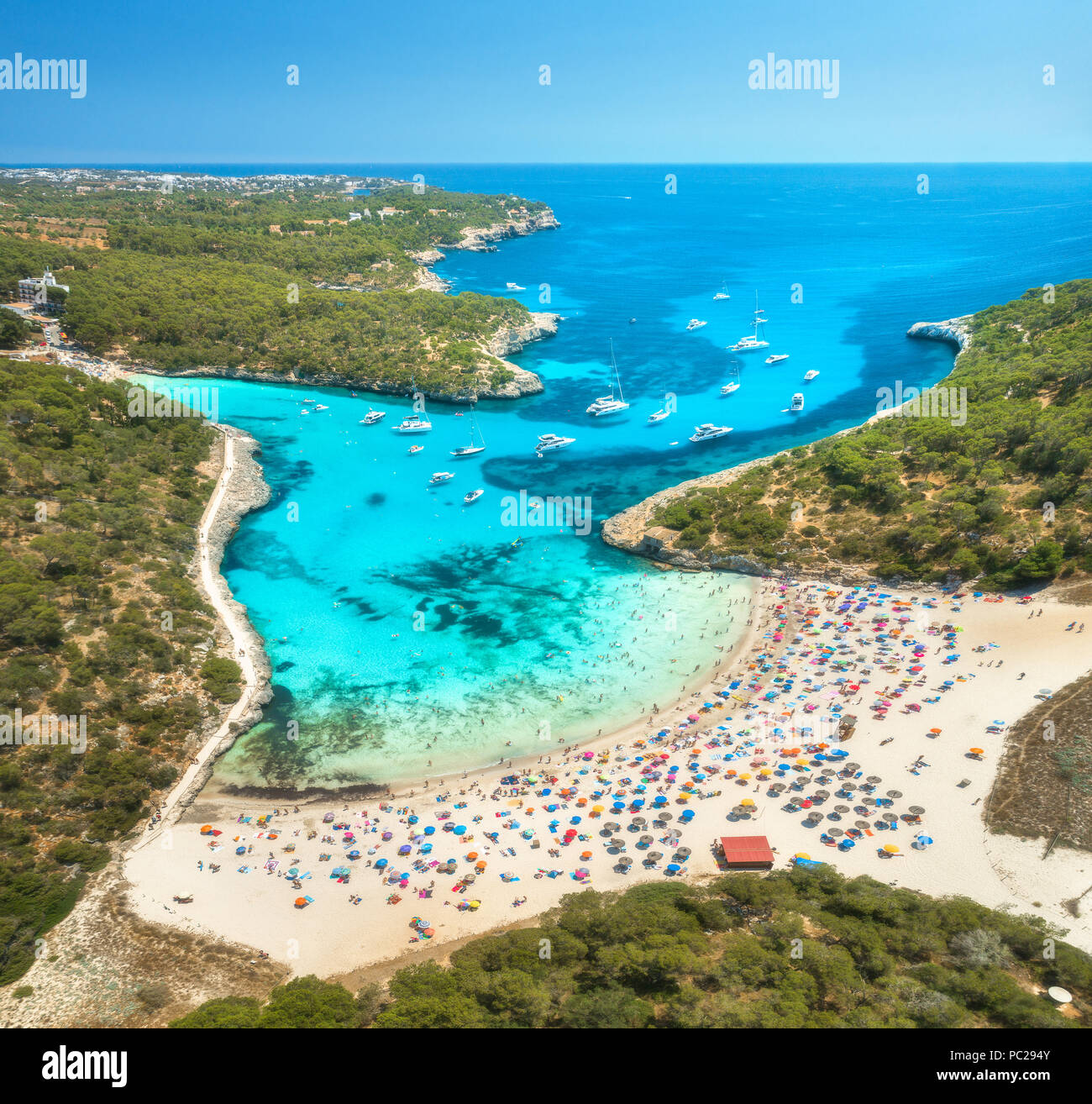 Vista aerea della spiaggia di sabbia fine attrezzata con ombrelloni colorati, persone, yacht e barche in mare baia con acqua blu, foresta nella mattina di sole. Viaggio estivo in Mal Foto Stock