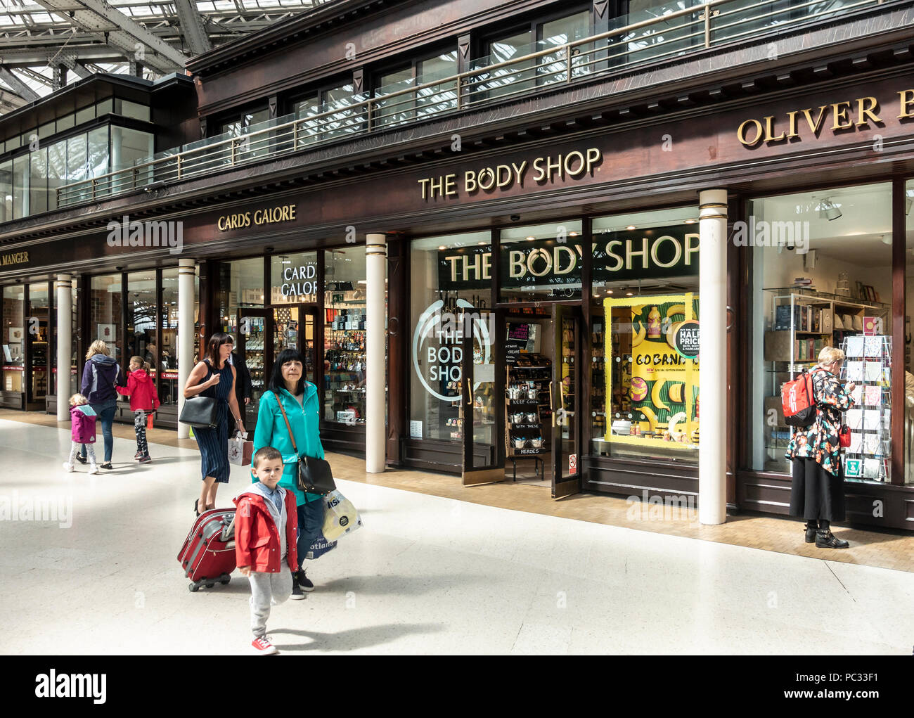 Passeggeri a piedi attraverso il piazzale della Stazione Centrale di Glasgow passato unità di vendita al dettaglio come il Body Shop, schede a bizzeffe, Oliver Bonas e Pret a rogna sarcoptica Foto Stock