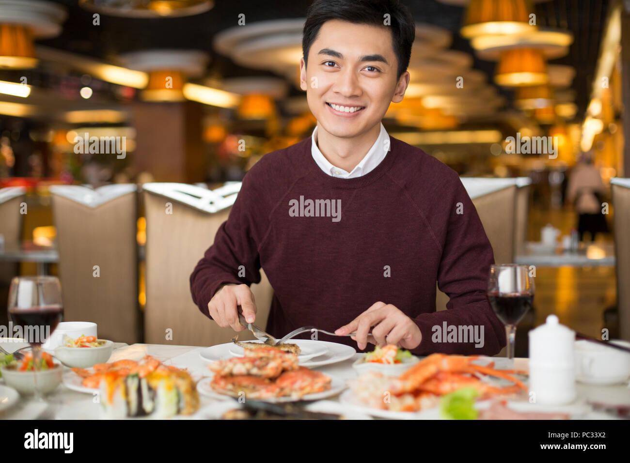 Allegro giovane uomo cinese avente una cena a buffet Foto Stock