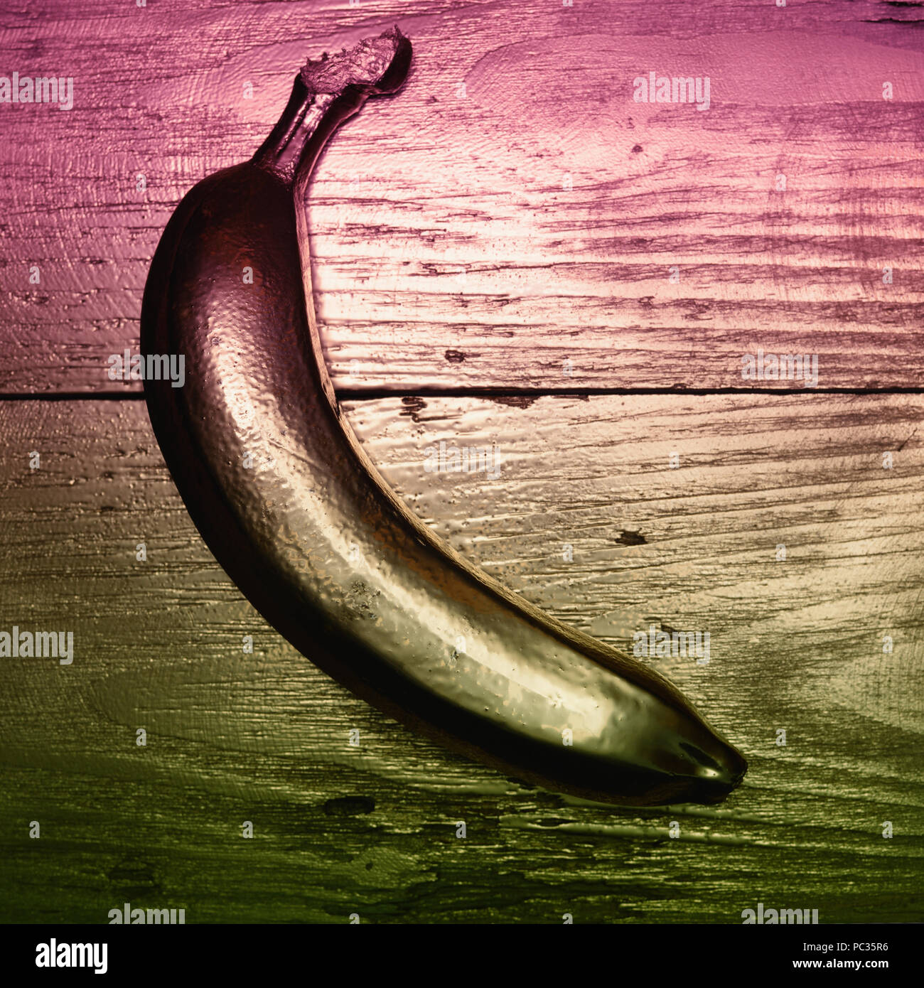 Oro dipinto di banana in oro e lo sfondo di legno. Il doppio filtro di colore. Foto Stock