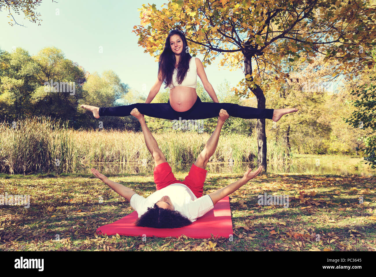 Autunno Park giovane facendo acro yoga. La gravidanza. Messa a fuoco selettiva Foto Stock
