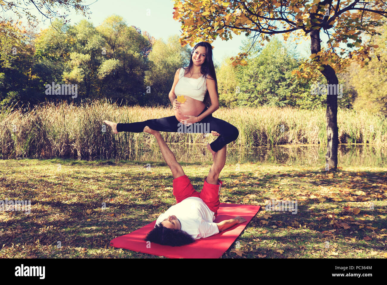 Autunno yoga nel parco l uomo e la donna incinta facendo acro yoga. Selevtive focus Foto Stock