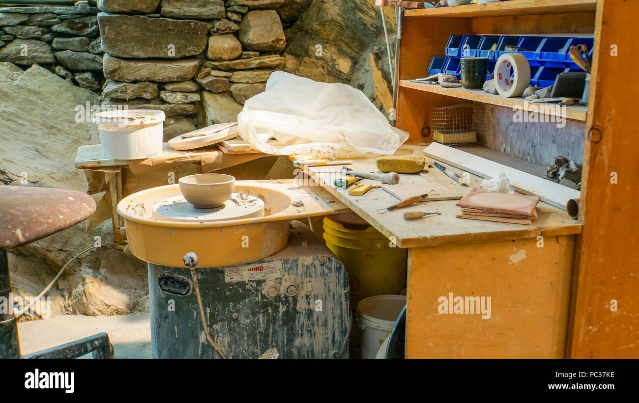 Potter's studio o workshop con ruota, strumenti, argilla, vaso in corso Foto Stock