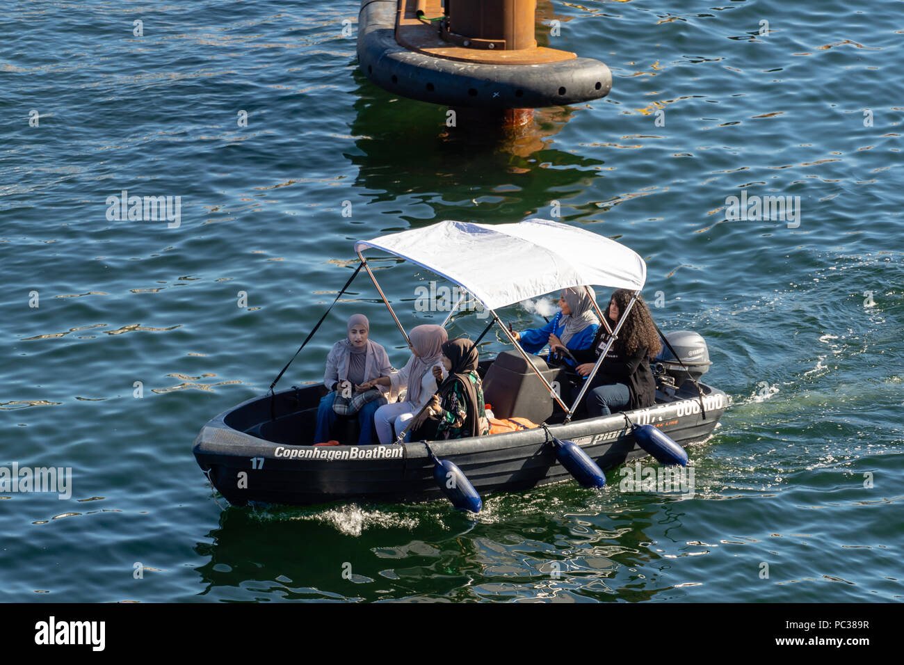 Giovani donne che indossano hijab in una barca nel porto di Copenaghen, controllo di telefoni cellulari e fumatori tubo acqua Foto Stock