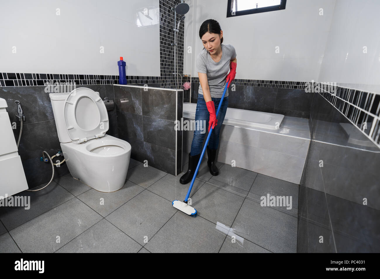 Donna che utilizza la spazzola per la pulizia della piastrella in bagno  Foto stock - Alamy