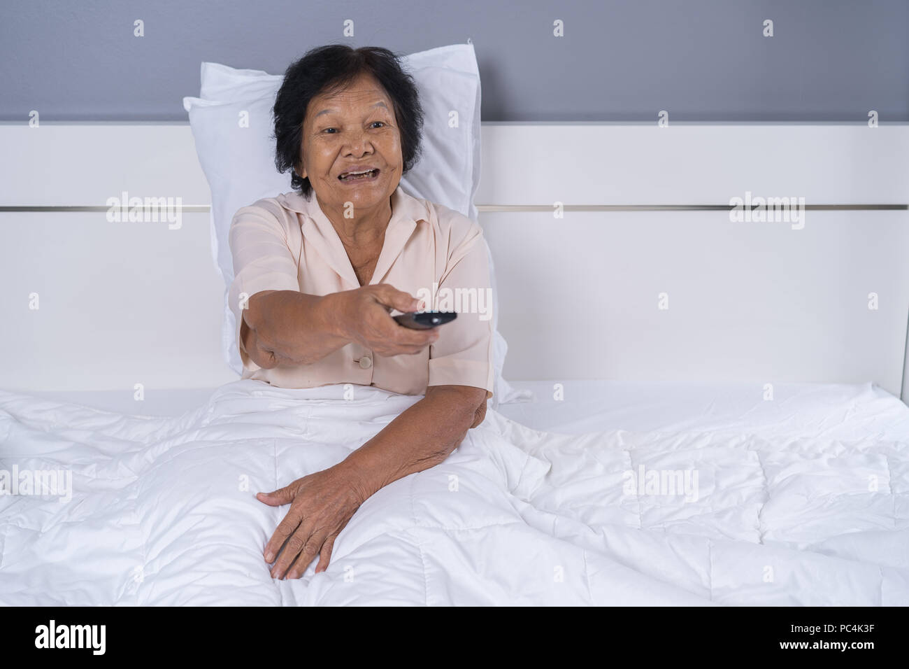 Felice senior donna nel letto con telecomando e guardare la tv Foto Stock