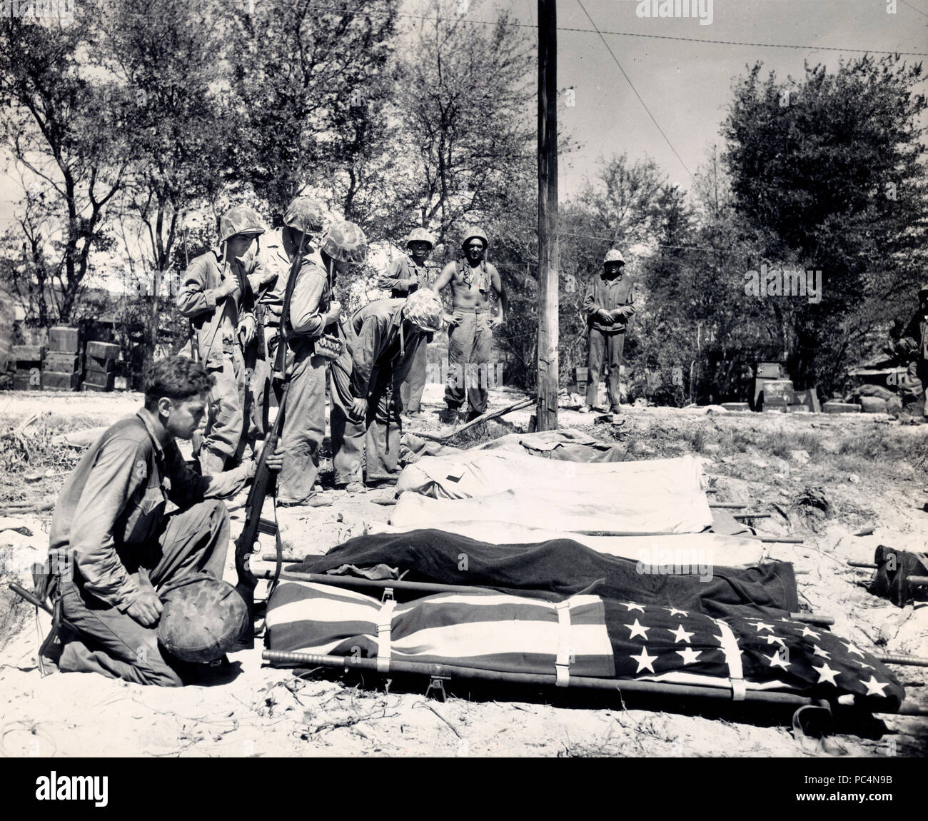 Marines dalla prima ondata di assalto su Saipan, dire addii di compagni caduti che sono preparati per la sepoltura Foto Stock