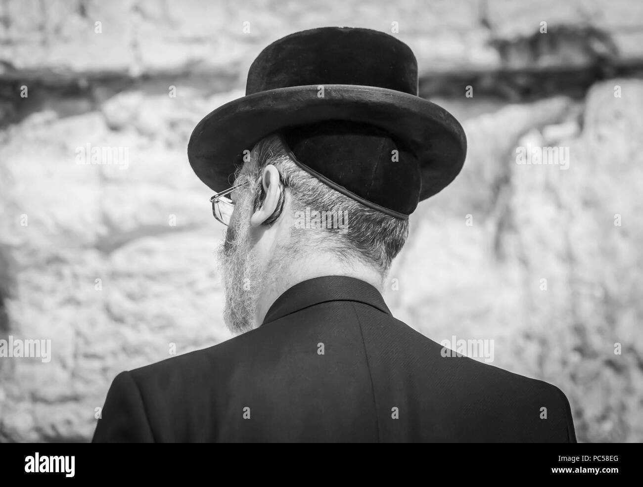 Ebrei Ortodossi uomo in preghiera presso il Muro del Pianto, muro occidentale in bianco e nero Concetto di immagine. Un religioso ebreo in una black hat e black suit. Foto Stock