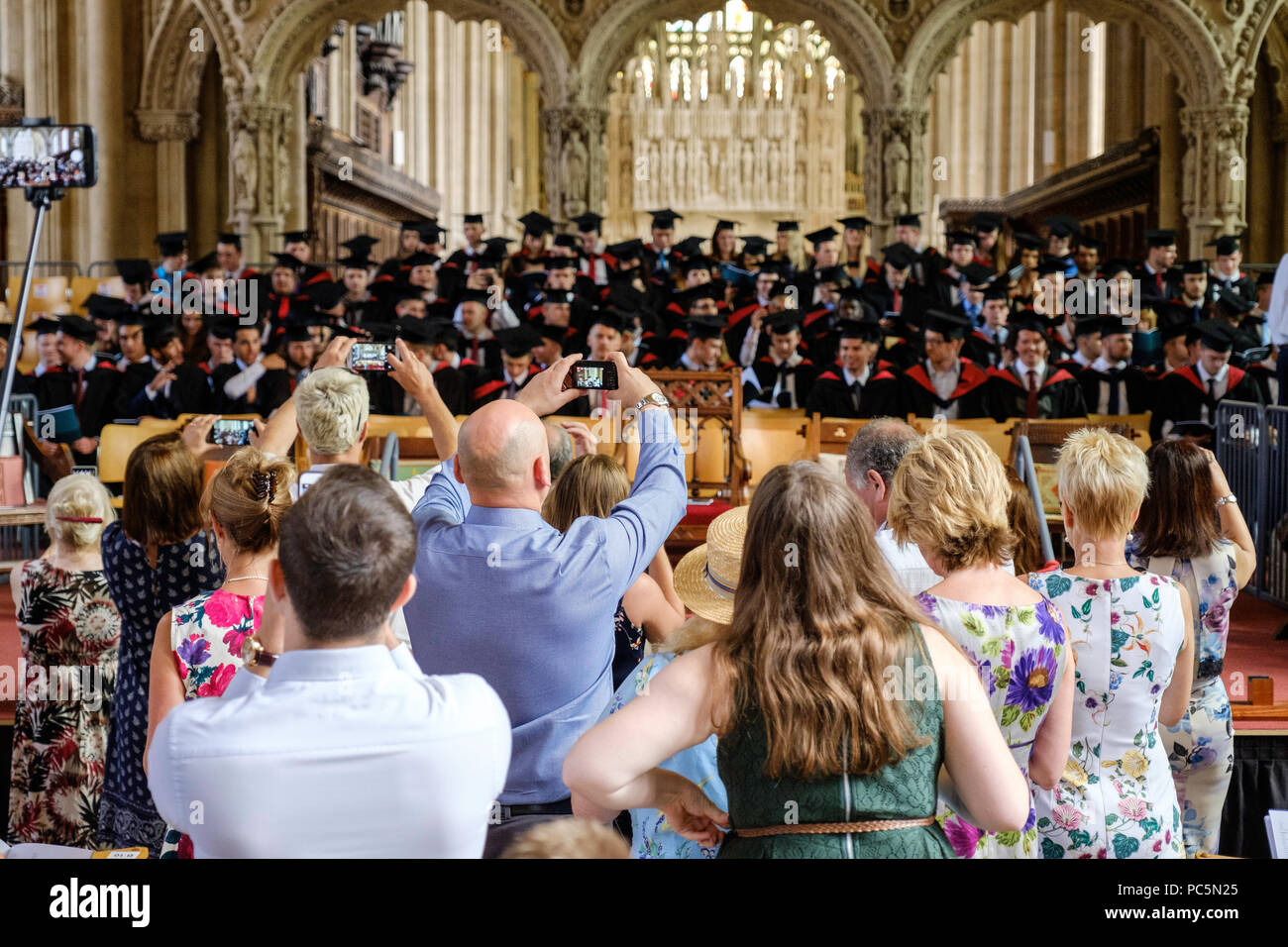 Cerimonia di laurea nella Cattedrale di Bristol luglio2018.laureati sul palco in malta-boards e gli abiti. Famiglie scattare fotografie Foto Stock