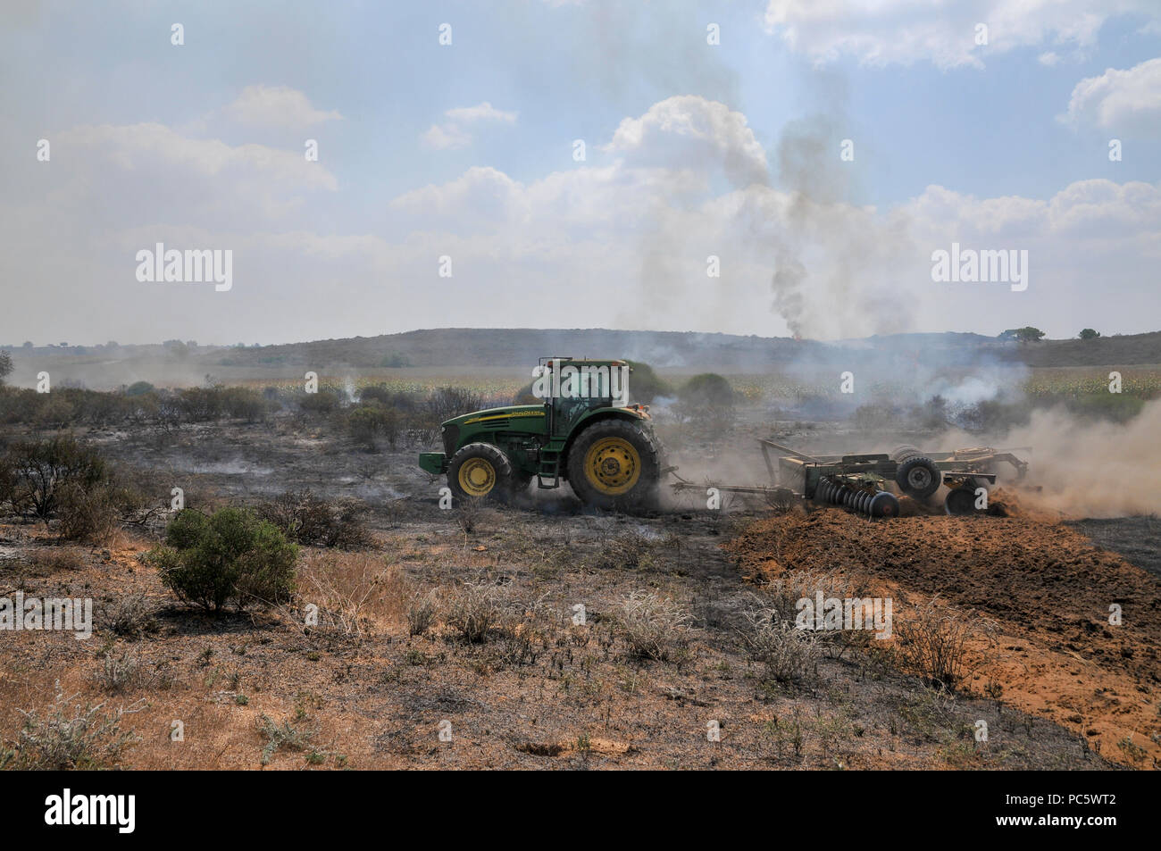 Contadino ara un campo di masterizzazione per contenere l'incendio. Questo incendio è stato causato da Kite palestinese bombe che sono state percorse da Gaza con un acceso imbevuto di benzina Foto Stock