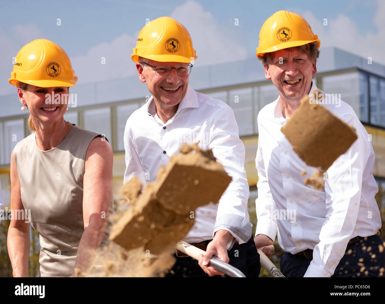 Il 31 luglio 2018, Germania, Hannover: Arianna Reinhart (L-R) Direttore Risorse Umane Officer di Continental AG, Elmar Degenhart, Chief Executive Officer di Continental AG e Wolfgang Schaefer, Chief Financial Officer di Continental AG, buttare sabbia in una pila durante la cerimonia di apertura per la nuova sede centrale continentale. Il nuovo Campus continentale sarà costituito da un totale di otto edifici. Essi saranno collegati da quattro ponti. Foto: Peter Steffen/dpa Foto Stock