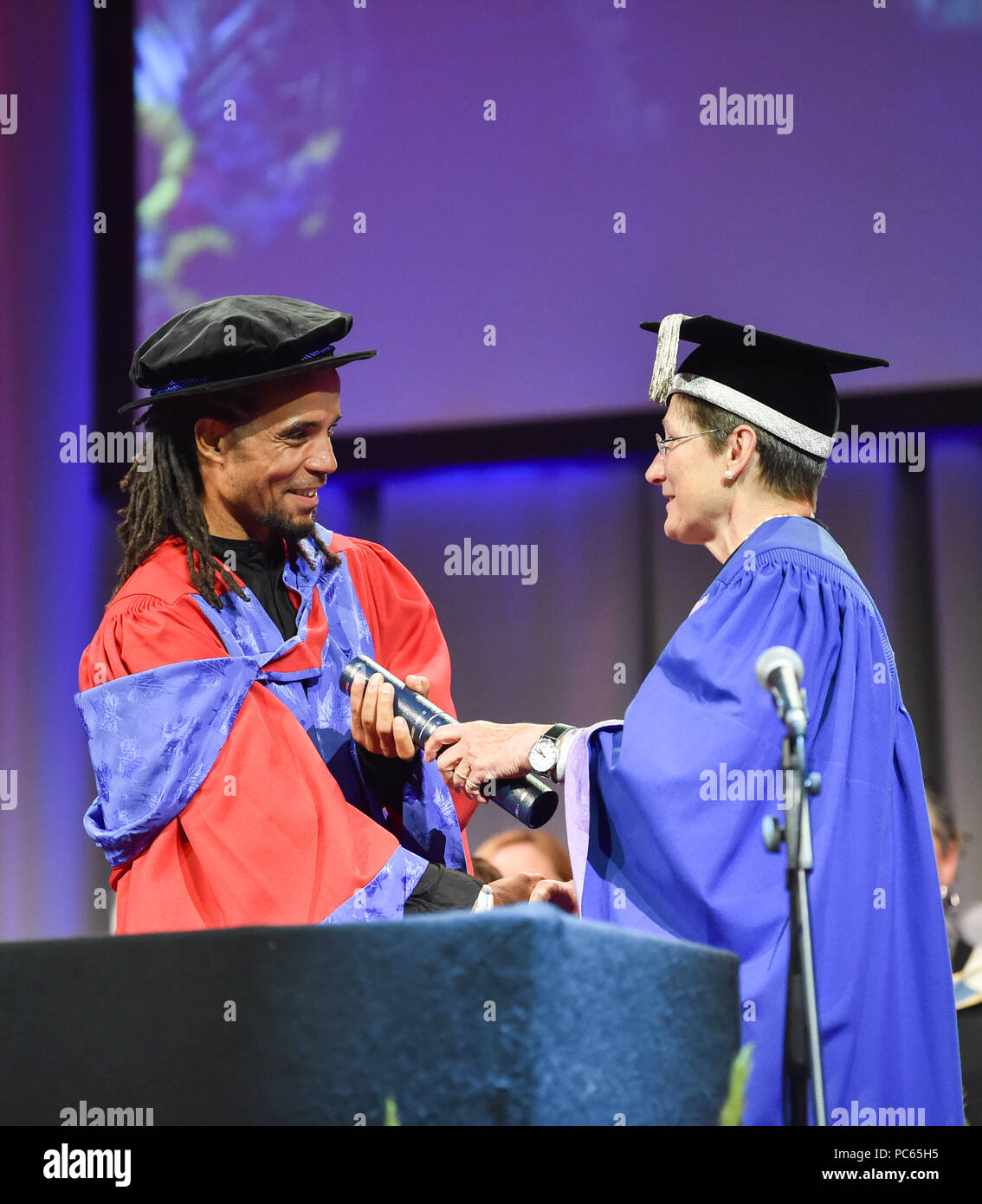 Brighton Regno Unito 31 luglio 2018 - il celebre rapper e scrittore Akala riceve un medico di arti in riconoscimento del suo importante contributo alla responsabilizzazione dei giovani attraverso l'apprendimento presso l'Università di Brighton cerimonia di laurea oggi . Il premio è stato consegnato dal Professor Debra Humphris il vicecancelliere dell'Università di Brighton Credito: Simon Dack/Alamy Live News Foto Stock