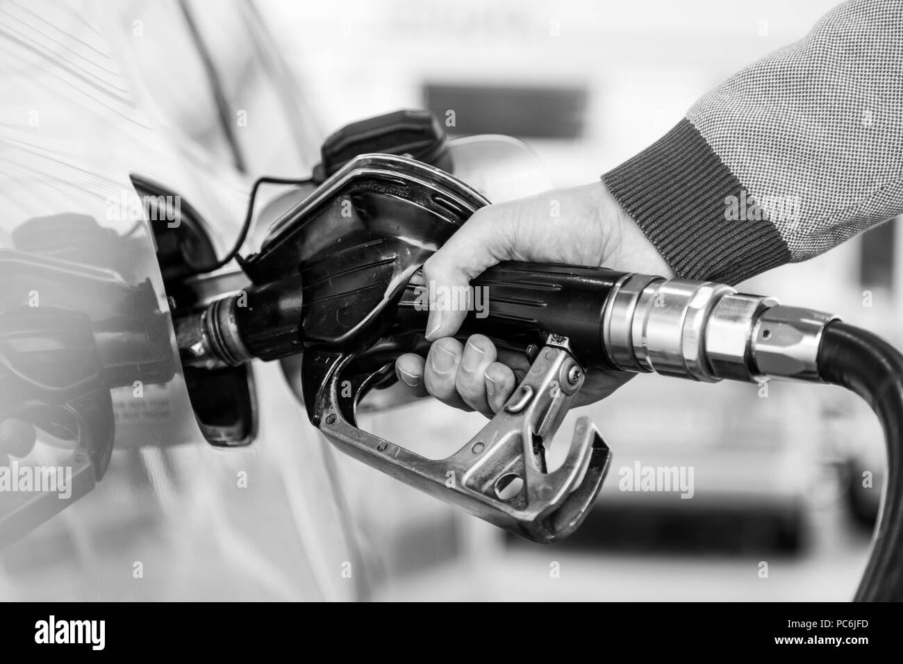 Primo piano della mano mans pompando benzina in auto alla stazione di gas. Foto Stock
