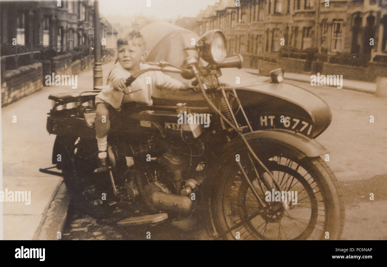 Vintage fotografia di un giovane ragazzo seduto su una motocicletta di grandi dimensioni Foto Stock