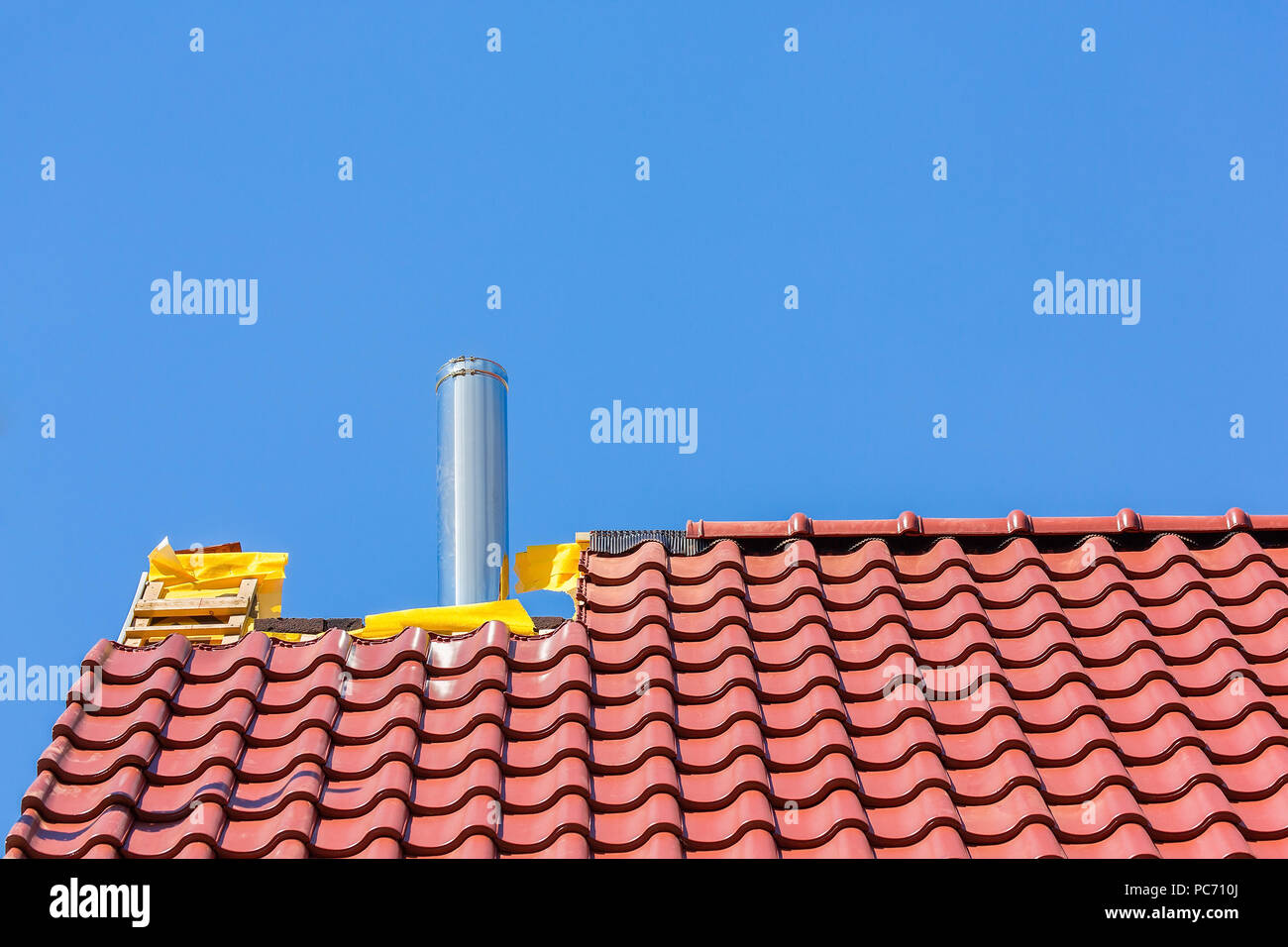 Il nuovo tetto con tegole e camino tubo contro il cielo blu Foto Stock