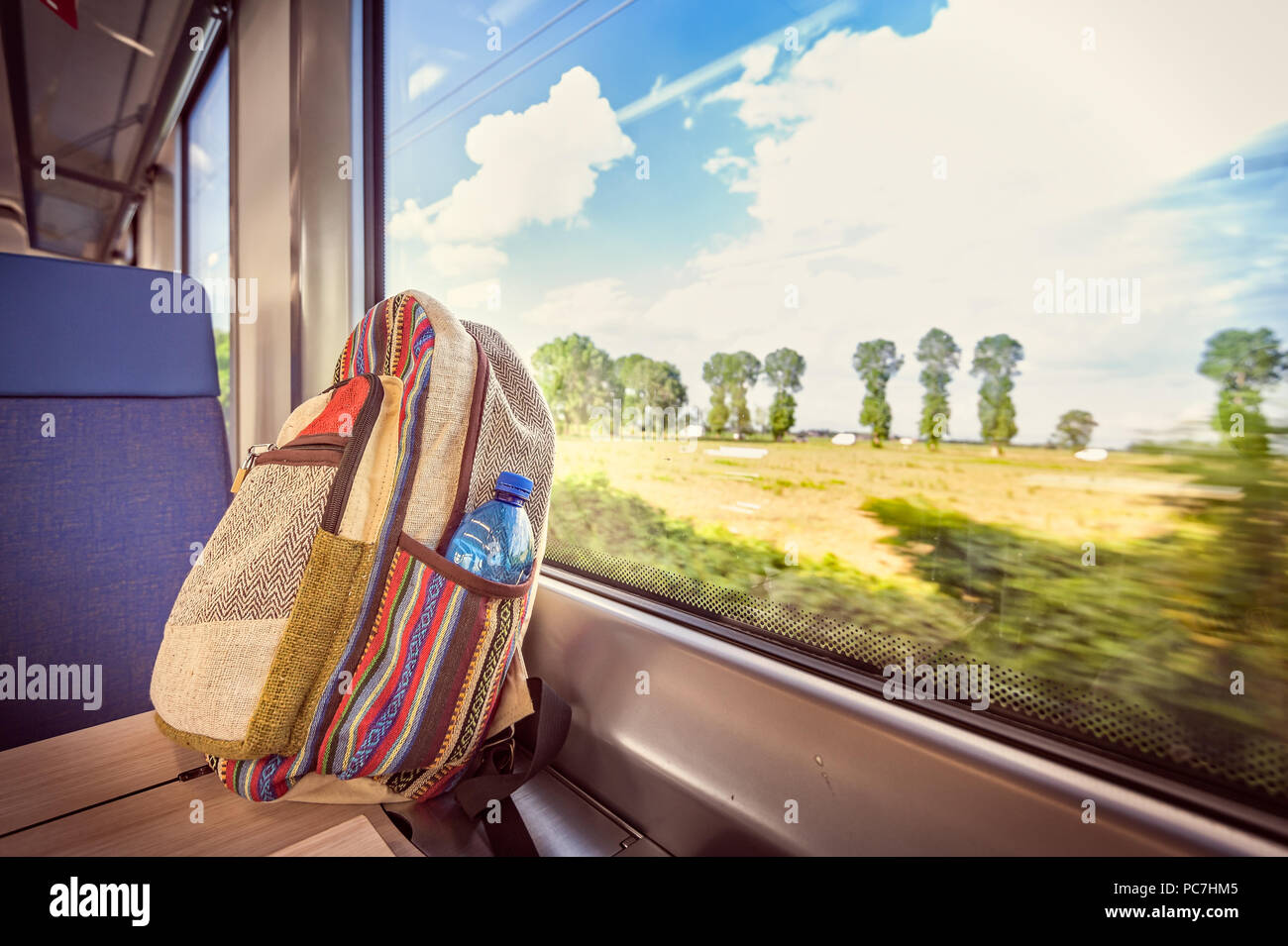 Zaino colorato sul treno vicino alla finestra. Immagine concettuale su come viaggiare in vacanza. Foto Stock