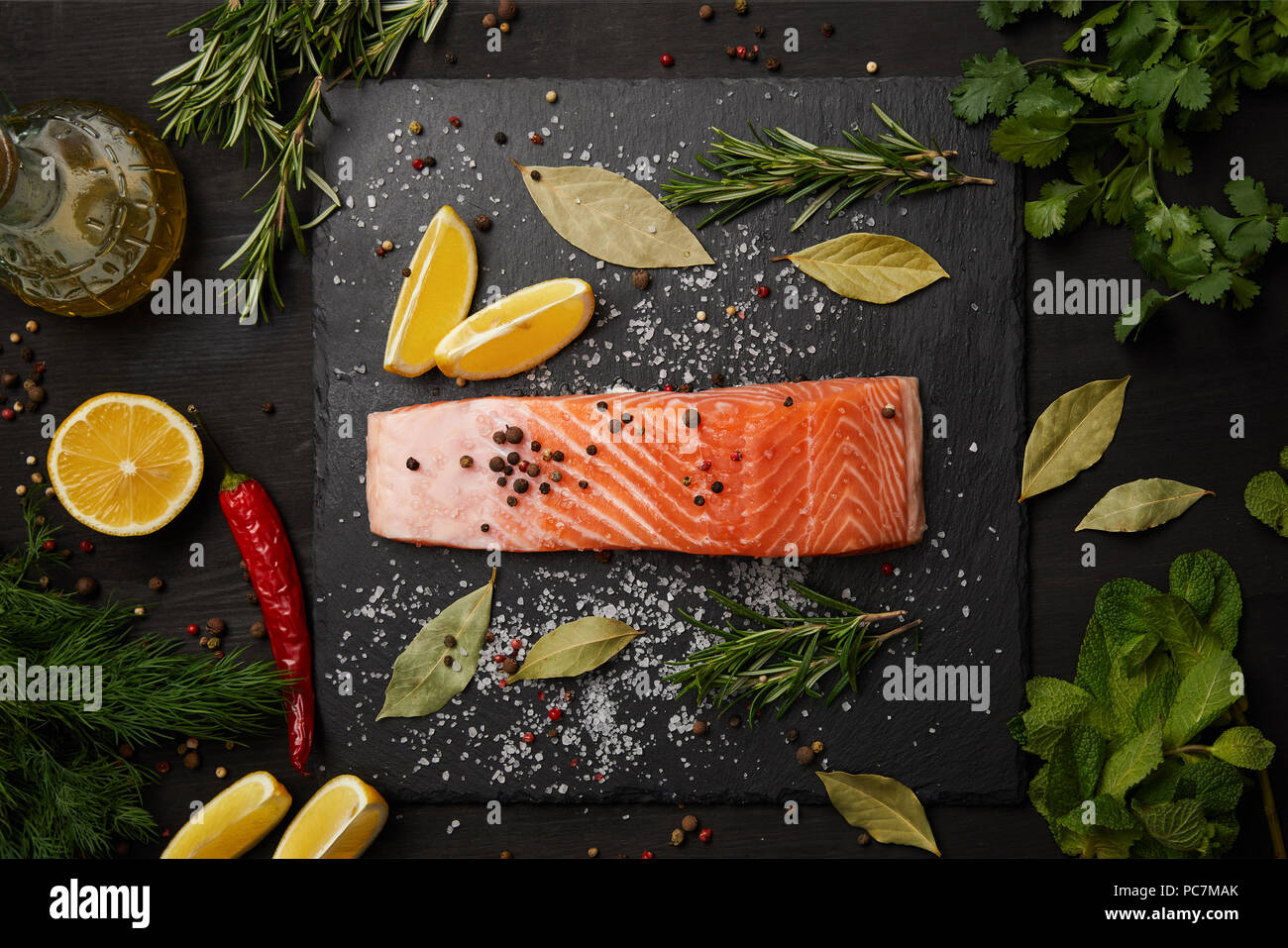 Materie salmone con erbe e limoni su sfondo di ardesia Foto Stock