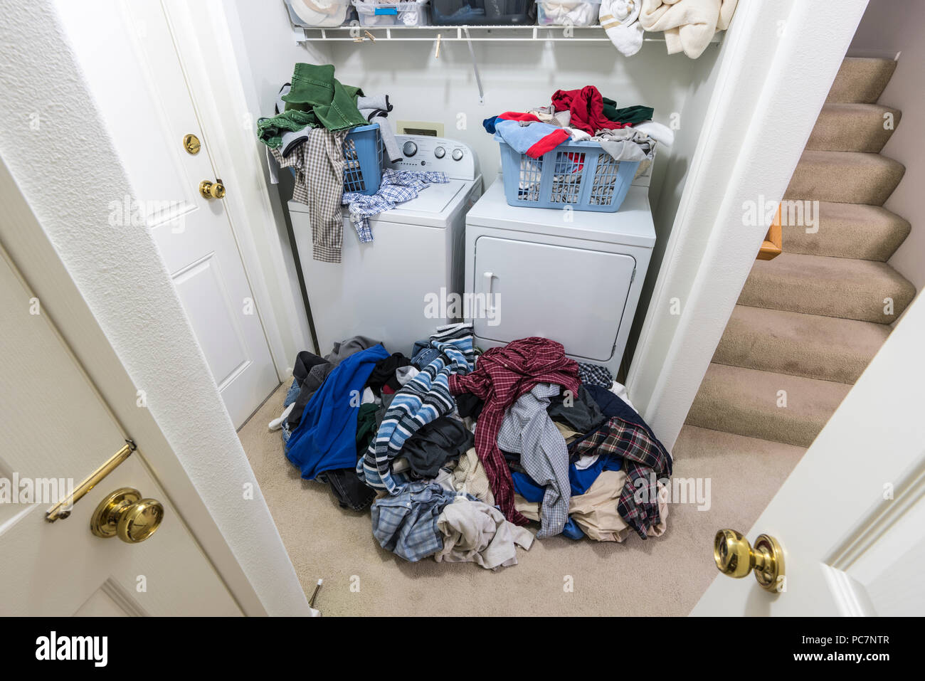 Ingombra confuso sala lavanderia con pile di vestiti che hanno bisogno di essere lavati. Foto Stock