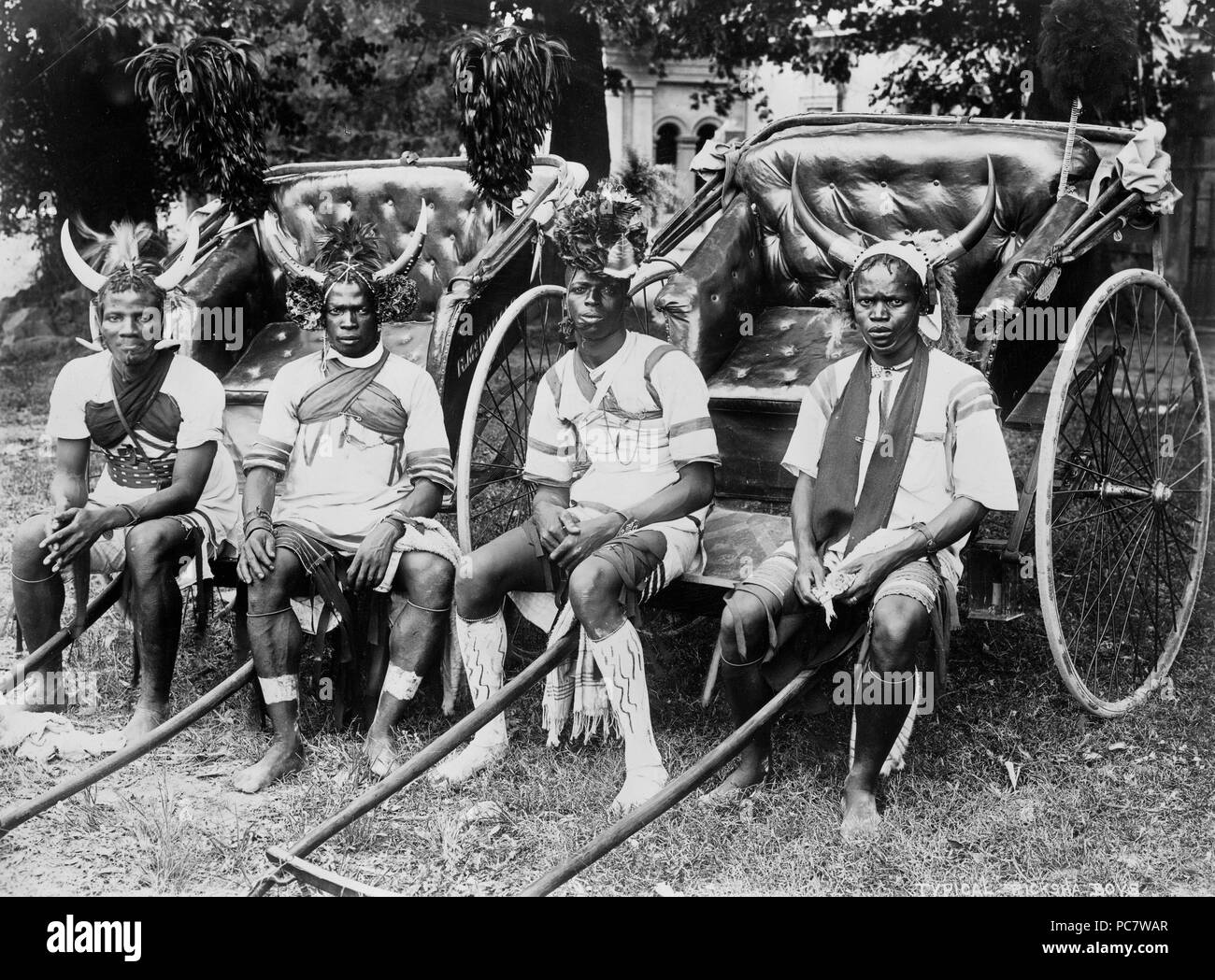 Ragazzi Ricksha Durban, Sout Africa 1890-1923 Foto mostra quattro giovani uomini seduti nella parte anteriore del riscio, rivolto verso la parte anteriore, tre sono cornuto da indossare copricapo e il quarto è che indossa un copricapo floreale. Foto Stock