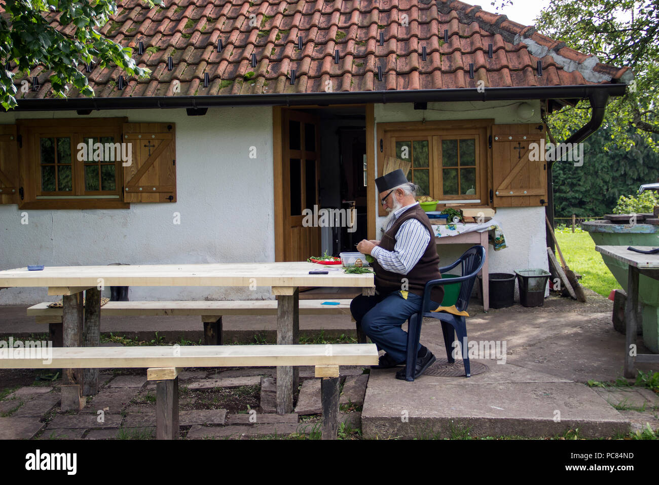 TARA National Park, Serbia 2018 - invecchiato un sacerdote ortodosso a preparare verdura da homegrown giardino davanti la sua casa collocata nel cortile della chiesa Foto Stock