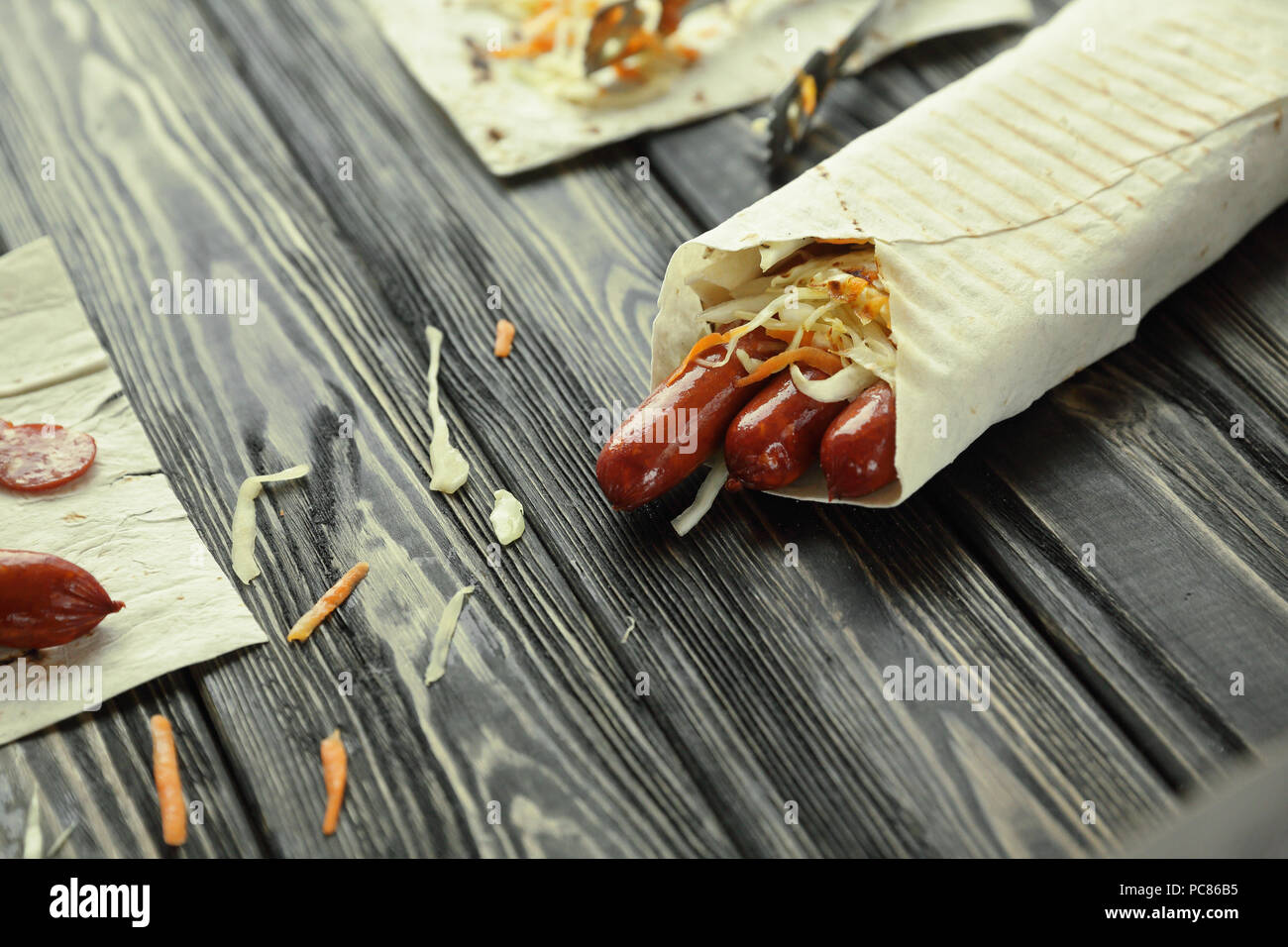 Salsiccia affumicata in pane pita su sfondo di legno Foto Stock