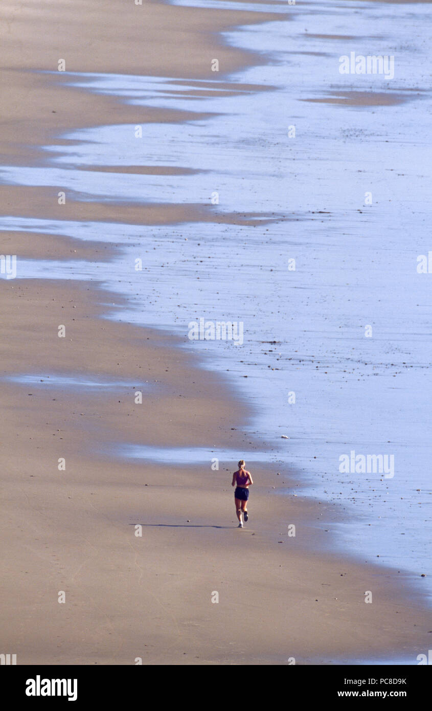 Una donna jogging sulla spiaggia. Foto Stock