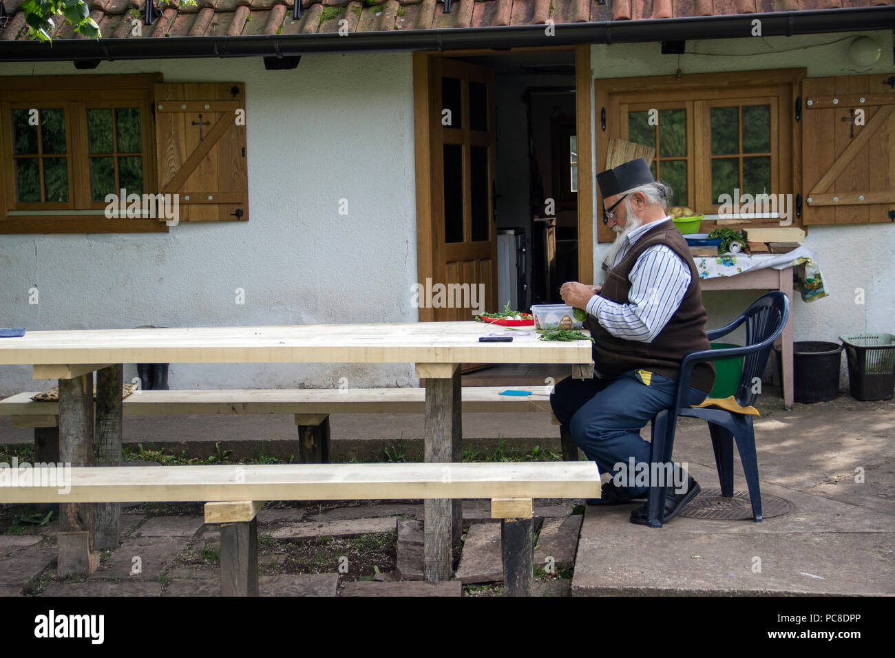TARA National Park, Serbia 2018 - invecchiato un sacerdote ortodosso a preparare verdura da homegrown giardino davanti la sua casa collocata nel cortile della chiesa Foto Stock
