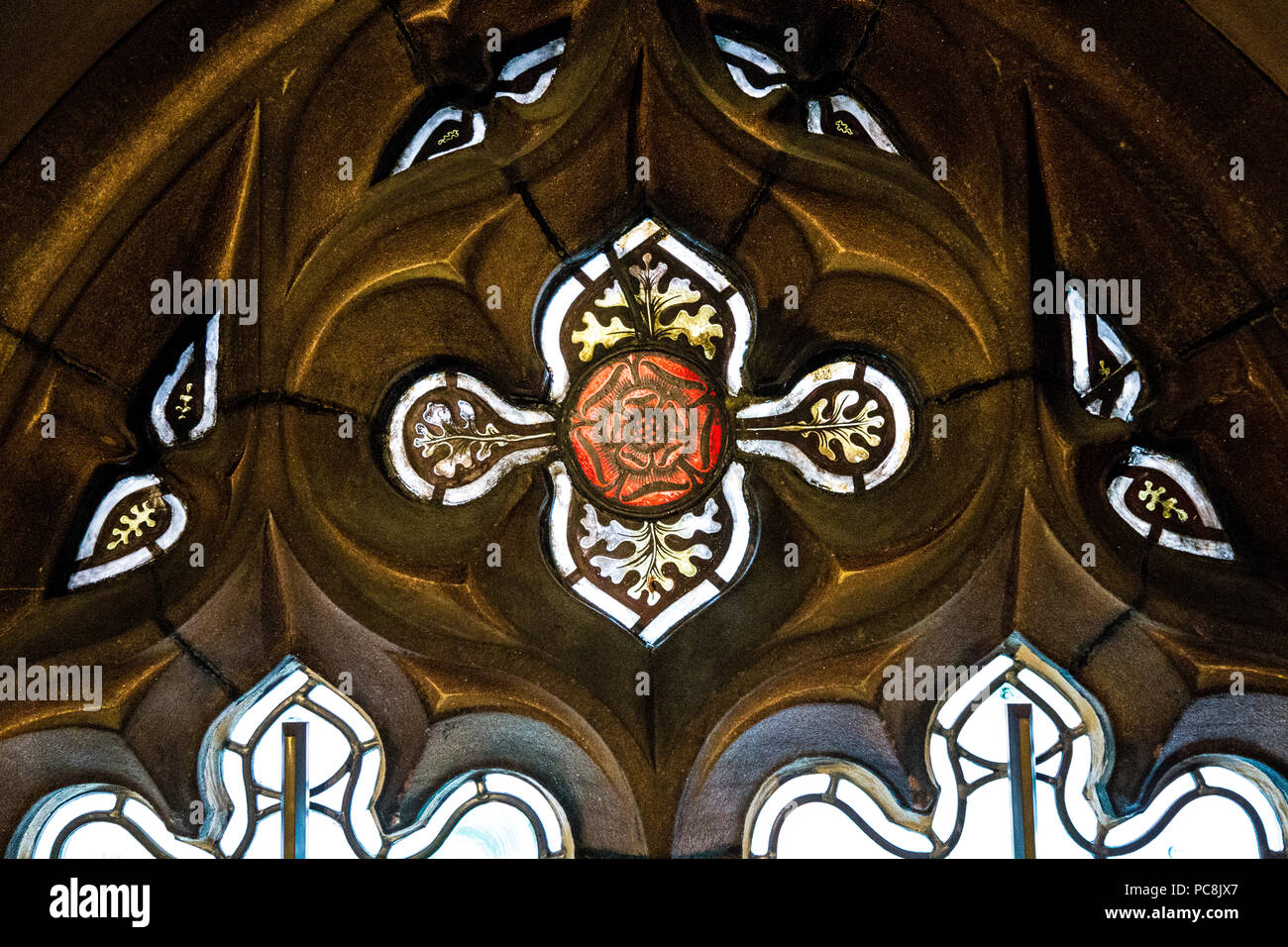 Una rosa rossa decorativi di vetro macchiato finestra in una cornice di pietra arenaria di John Rylands Library e Manchester, Regno Unito Foto Stock