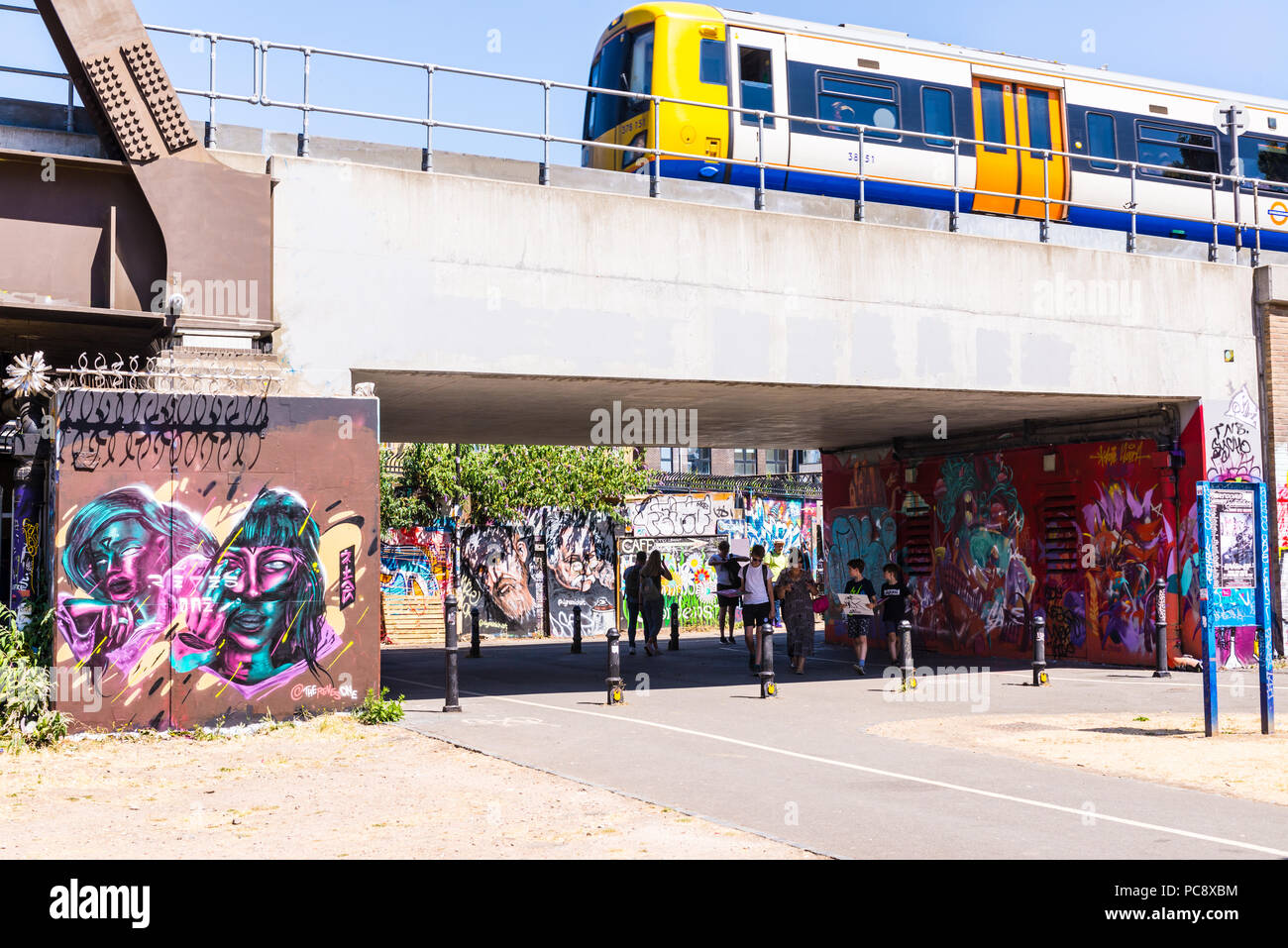 Ponte ferroviario vicino a Brick Lane con gente che cammina verso la nuova comunità di nomadi garden Foto Stock