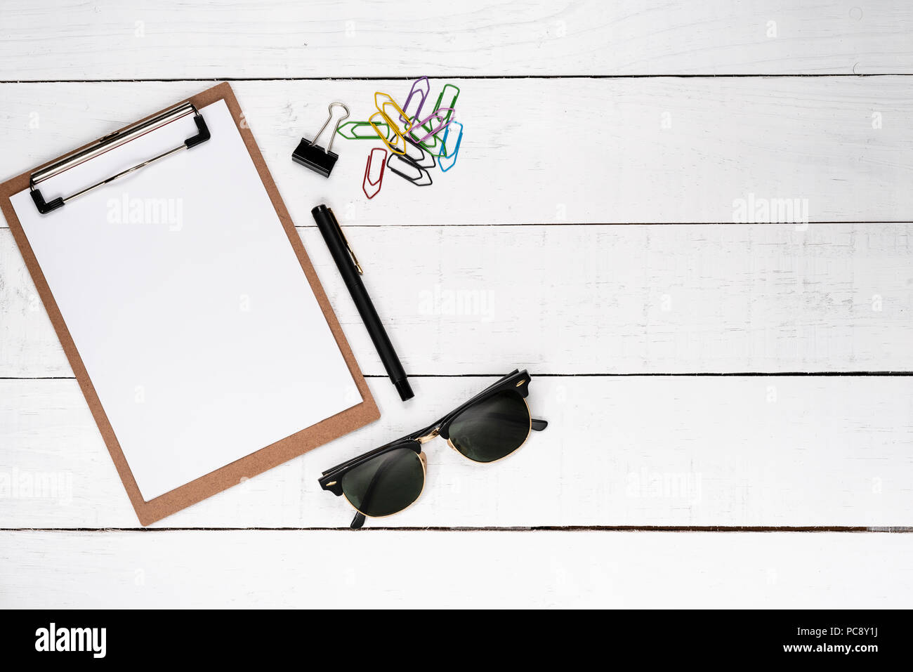 Vuoto il blocco note con penna stilografica, varie clip di carta e occhiali scuri su bianco sullo sfondo di legno Foto Stock