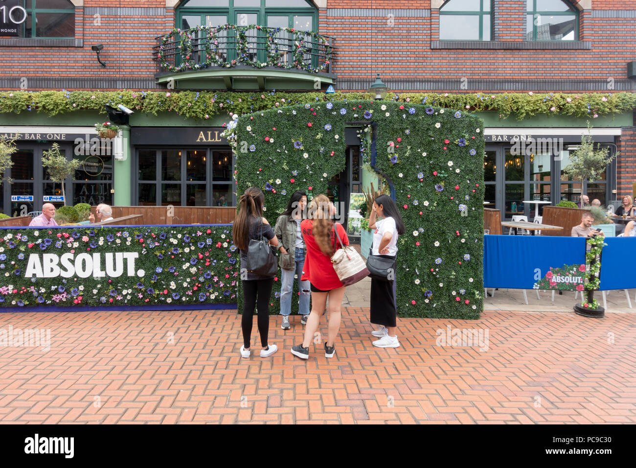 Quattro giovani donne in piedi al di fuori dell'Absolut terrazza del bar tutti uno restaraurant in Brindleyplace, centro della città di Birmingham, Inghilterra, Regno Unito Foto Stock