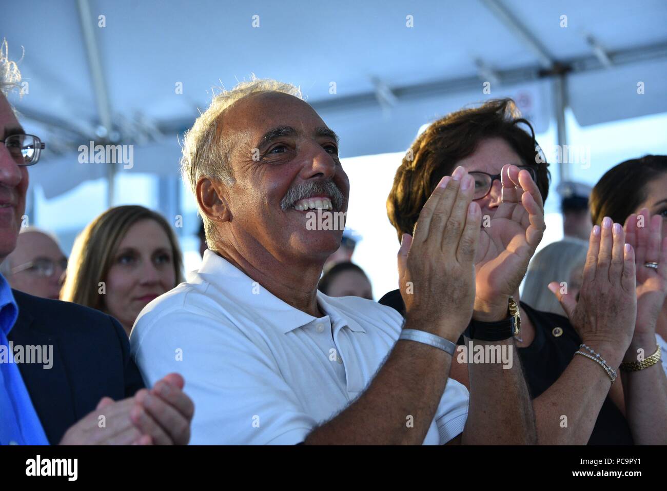 Rick Bruckenthal applausi a scena aperta a seguito di sua figlia Noabeth Bruckenthal il discorso durante la cerimonia di messa in servizio di guardacoste Nathan Bruckenthal in Old Town Alexandria, Virginia, luglio 25, 2018, 25 luglio 2018. Bruckenthal è la Guardia Costiera 28 della risposta veloce taglierina chiamato dopo Coast Guard Petty Officer di terza classe Nathan Bruckenthal, che è stato ferito a morte durante l'Operazione Iraqi Freedom nel Golfo Arabico nel 2004. Stati Uniti Coast Guard foto di Sottufficiali di prima classe Jetta discoteca. Immagine cortesia Petty Officer 1. Classe Jetta discoteca/STATI UNITI Quartier generale della guardia costiera. () Foto Stock