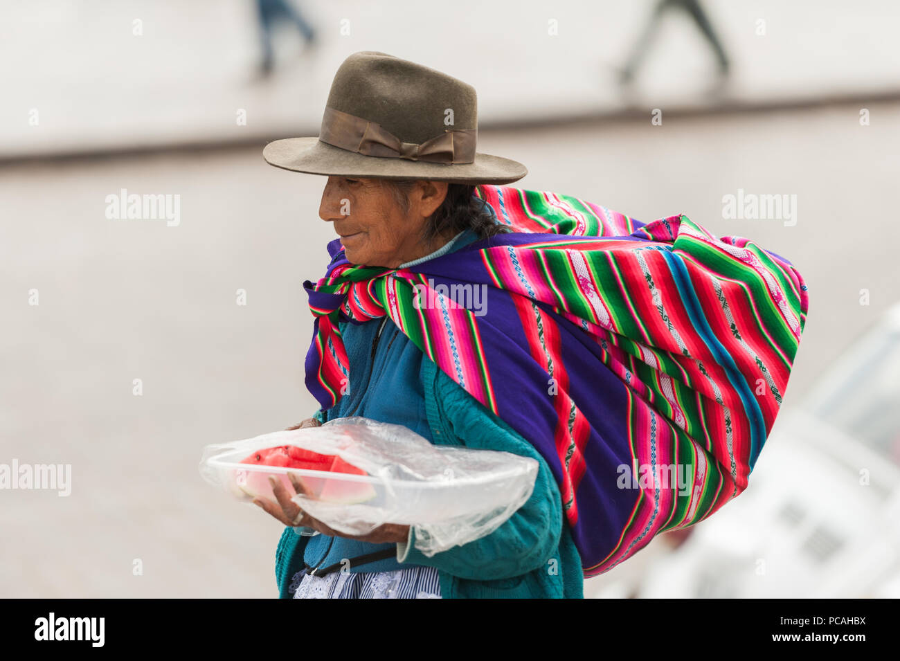 Donna locale la vendita di frutta e verdura e prelibatezze locali. Visualizzato su un contatore a un vintage mercato Sud Americano. Cusco, Perù Foto Stock